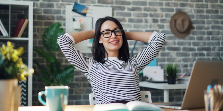 portrait of happy young woman relaxing in offce with cup of coffee