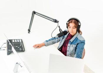 Woman recording podcast looking surprised with microphone