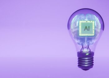Conceptual render of artificial intelligence processor chip embedded in a white human brain inside a transparent light bulb, floating against blue purple gradient background with copy space