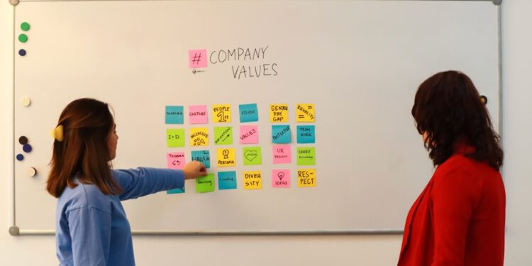 Two employees discussing company values written on sticky notes