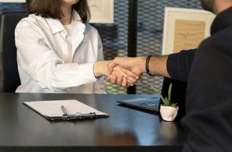 Ondernemer schudt de hand van een nieuwe medewerker in een klein kantoor