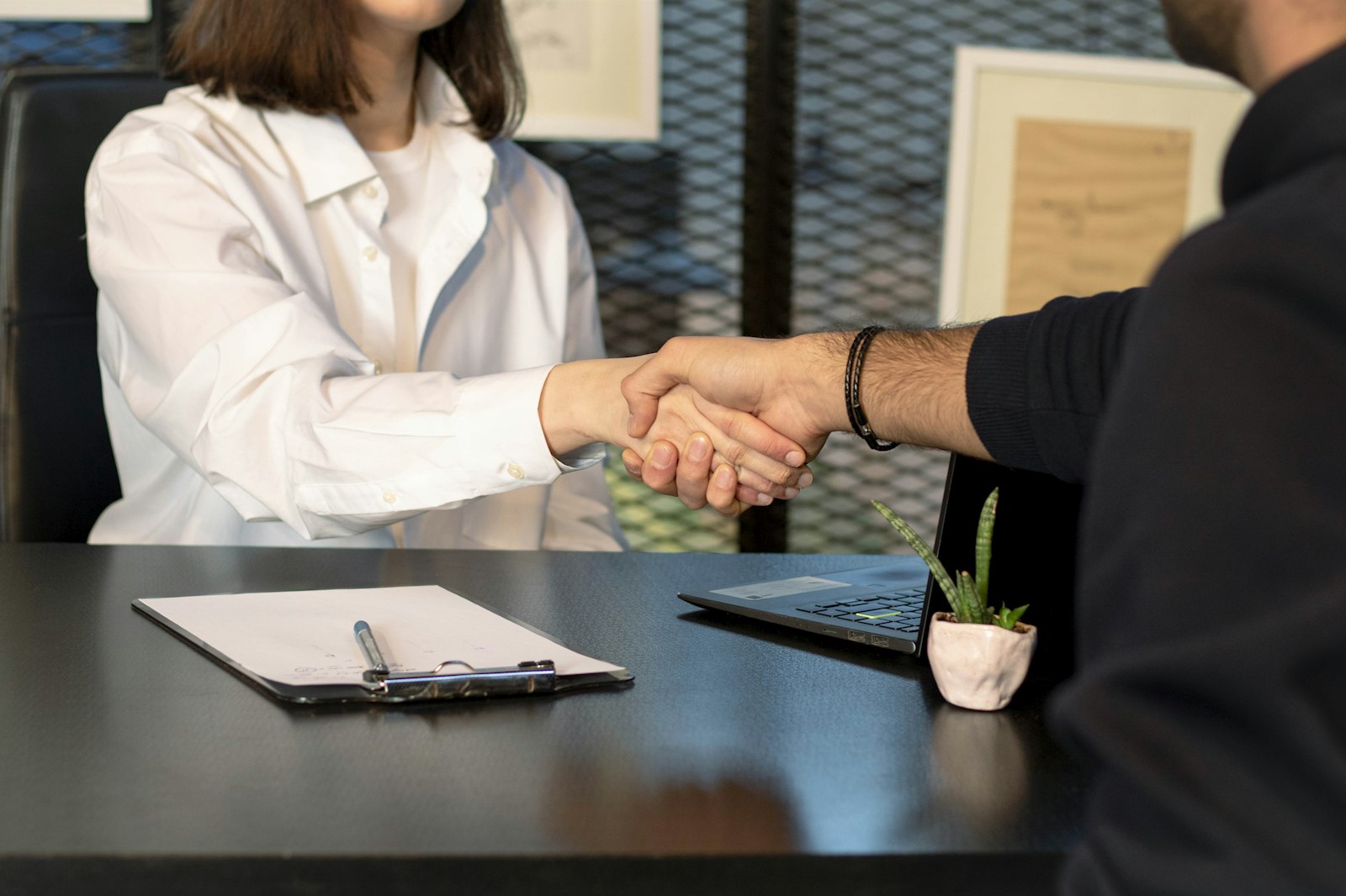 Ondernemer schudt de hand van een nieuwe medewerker in een klein kantoor