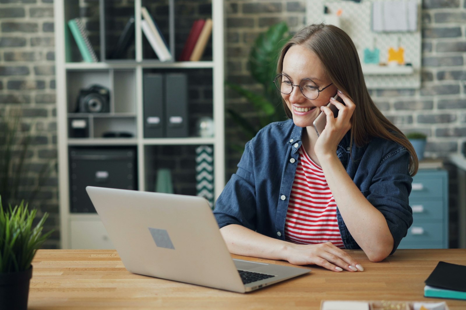 Vrouw belt zakelijk met haar mobiele telefoon achter een laptop