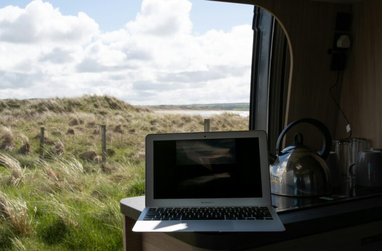 Ondernemer met een laptop naast een witte bestelbus