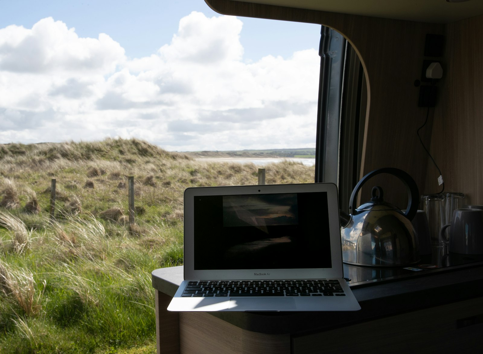 Ondernemer met een laptop naast een witte bestelbus