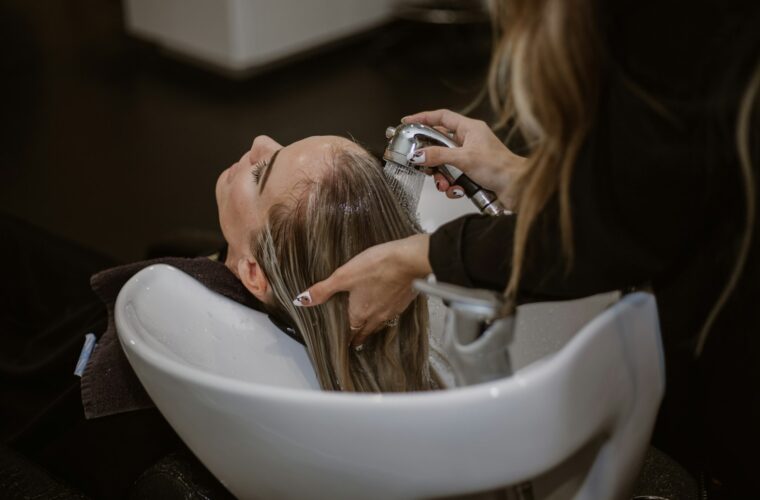 Kapper spoelt het haar van een klant bij de wasbak in een kapsalon