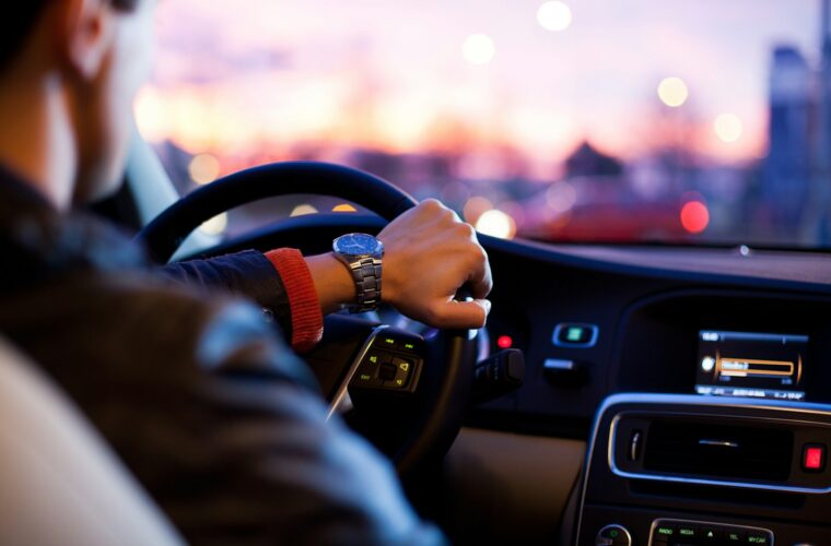 Hand aan het stuur van een auto tijdens een rit over de weg