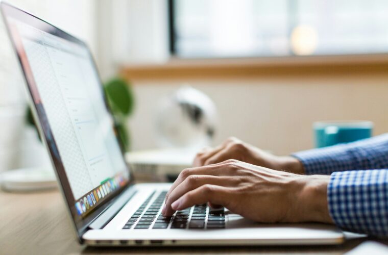 Zzp'er bekijkt zijn zakelijke bankrekening op een laptop met een betaalpas in de hand