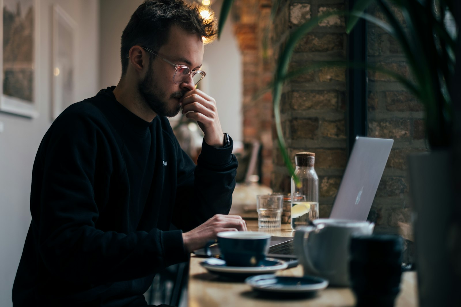 Zieke ondernemer met een kop thee achter zijn laptop aan de keukentafel